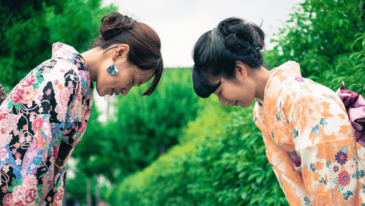 Deux femmes japonaises en kimono s’inclinent respectueusement l’une devant l’autre, illustrant une salutation traditionnelle japonaise.