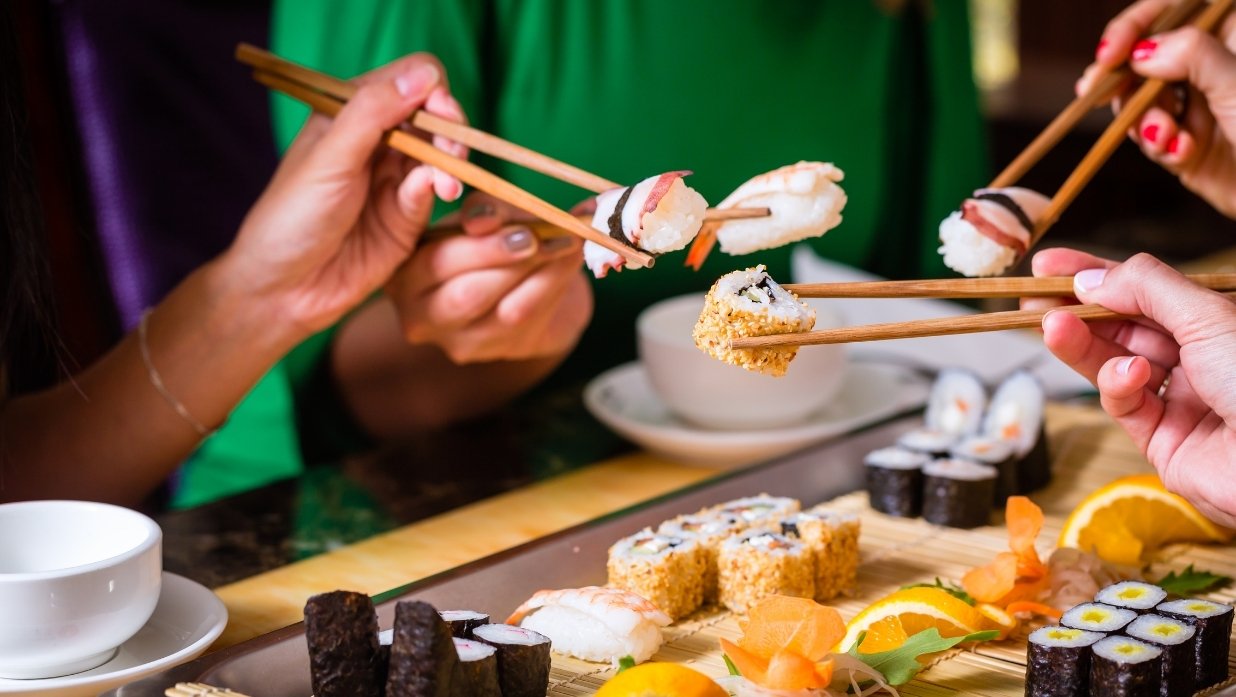 A group of friends eating sushi together.
