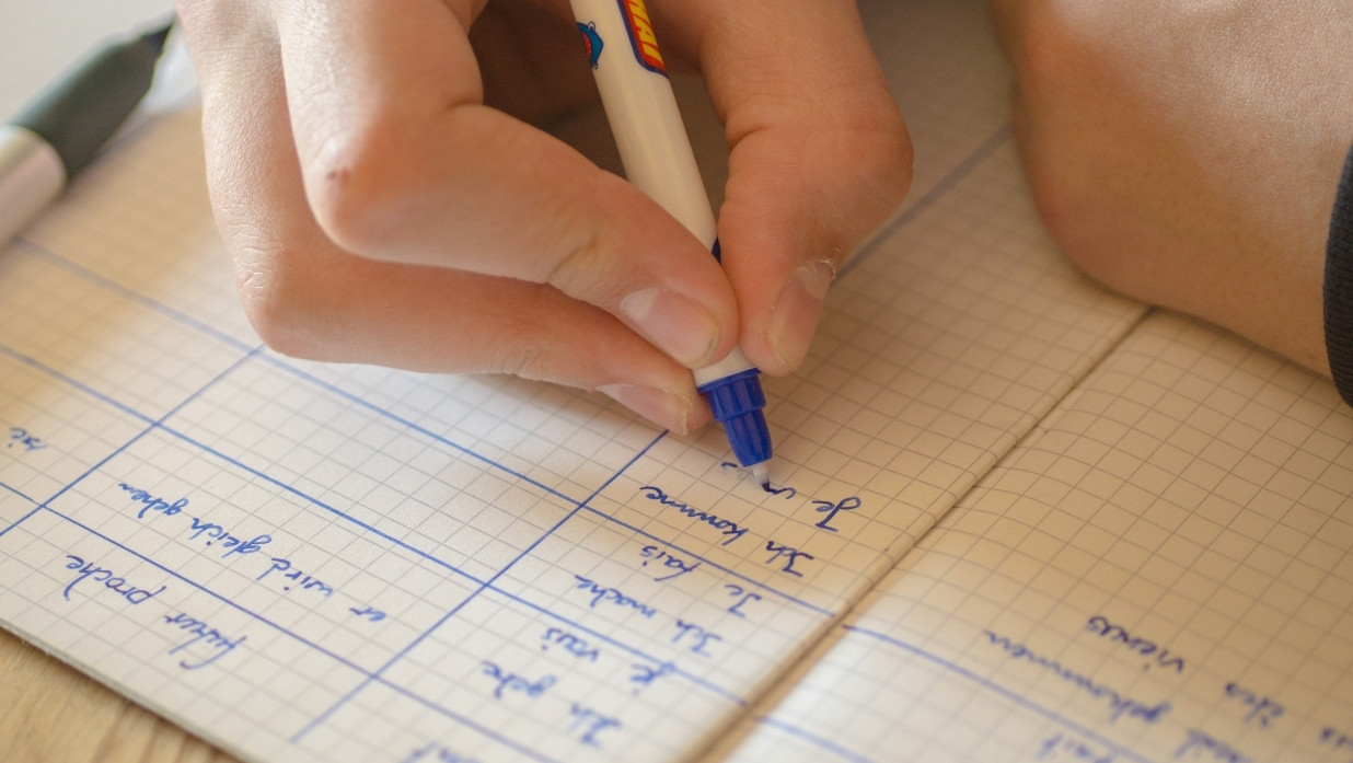 Person writing and practicing verb use