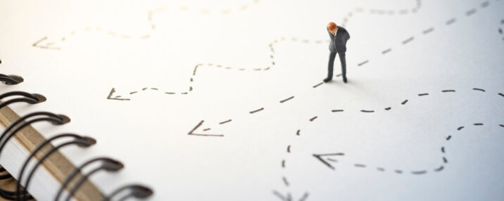 A figurine looking down at different drawn out directions on a paper.