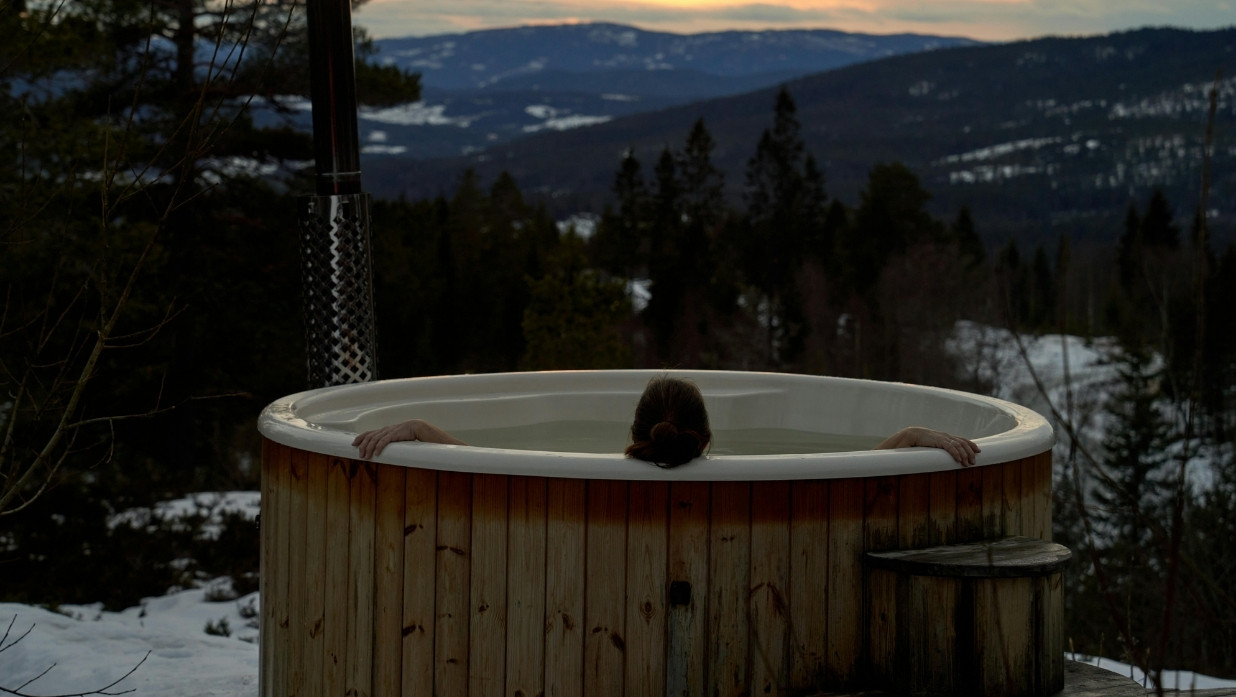 Woman in a hot tub looking over beautiful mountains.