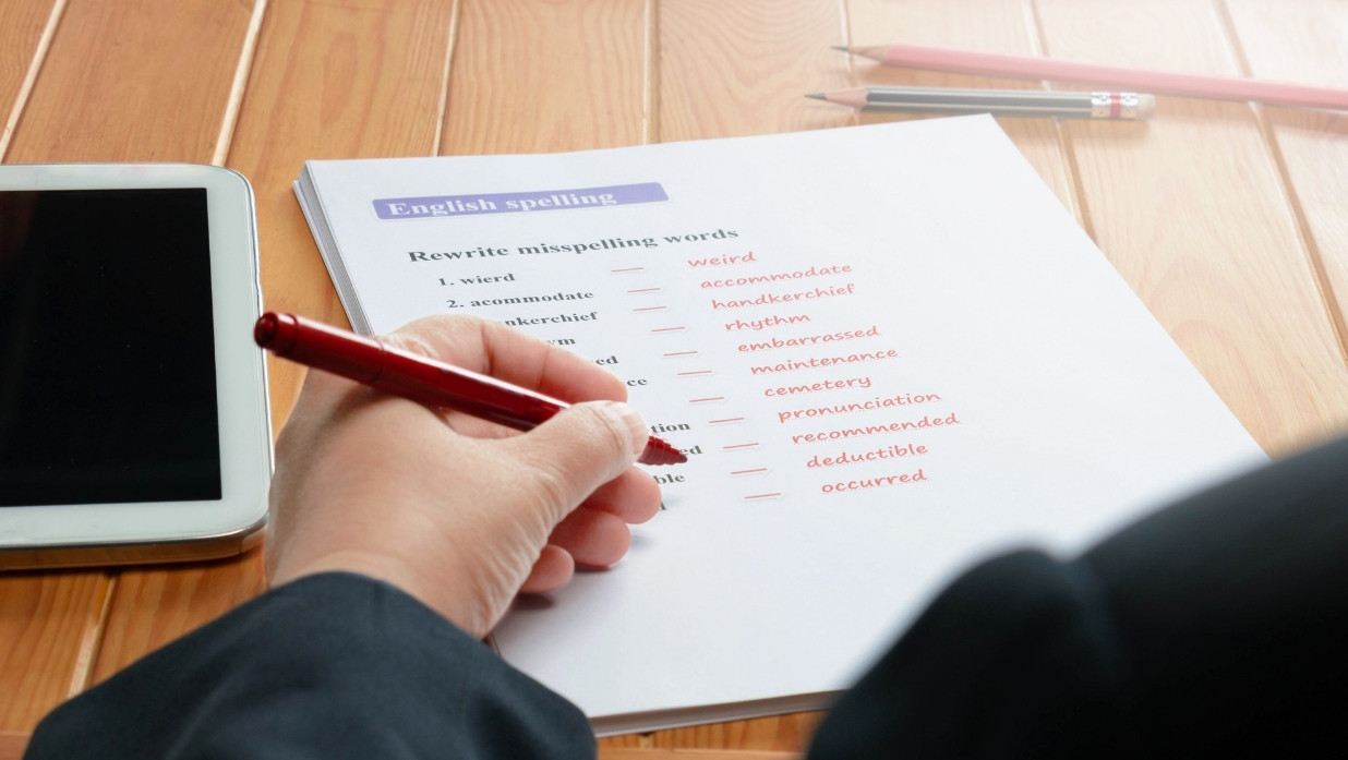 Person working on a worksheet with a red pen.