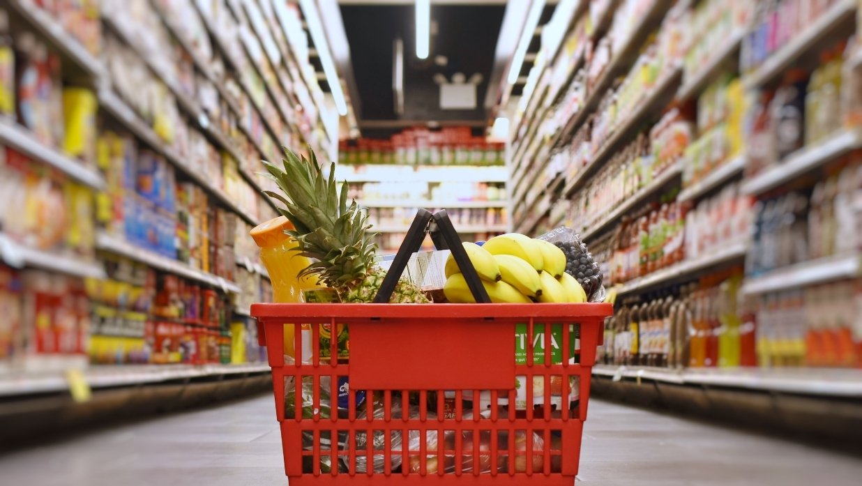 Grocery cart in the middle of an aisle in a grocery store. Food on sides.