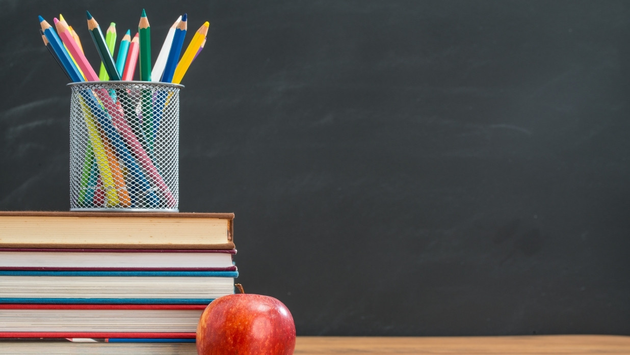 Textbooks, an apple, and pencils.