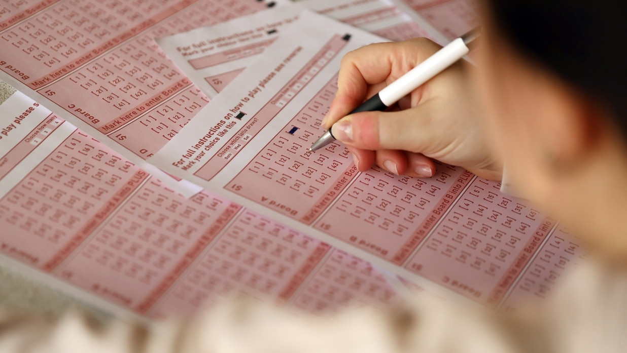 Person filling out a bubble sheet with a pen.
