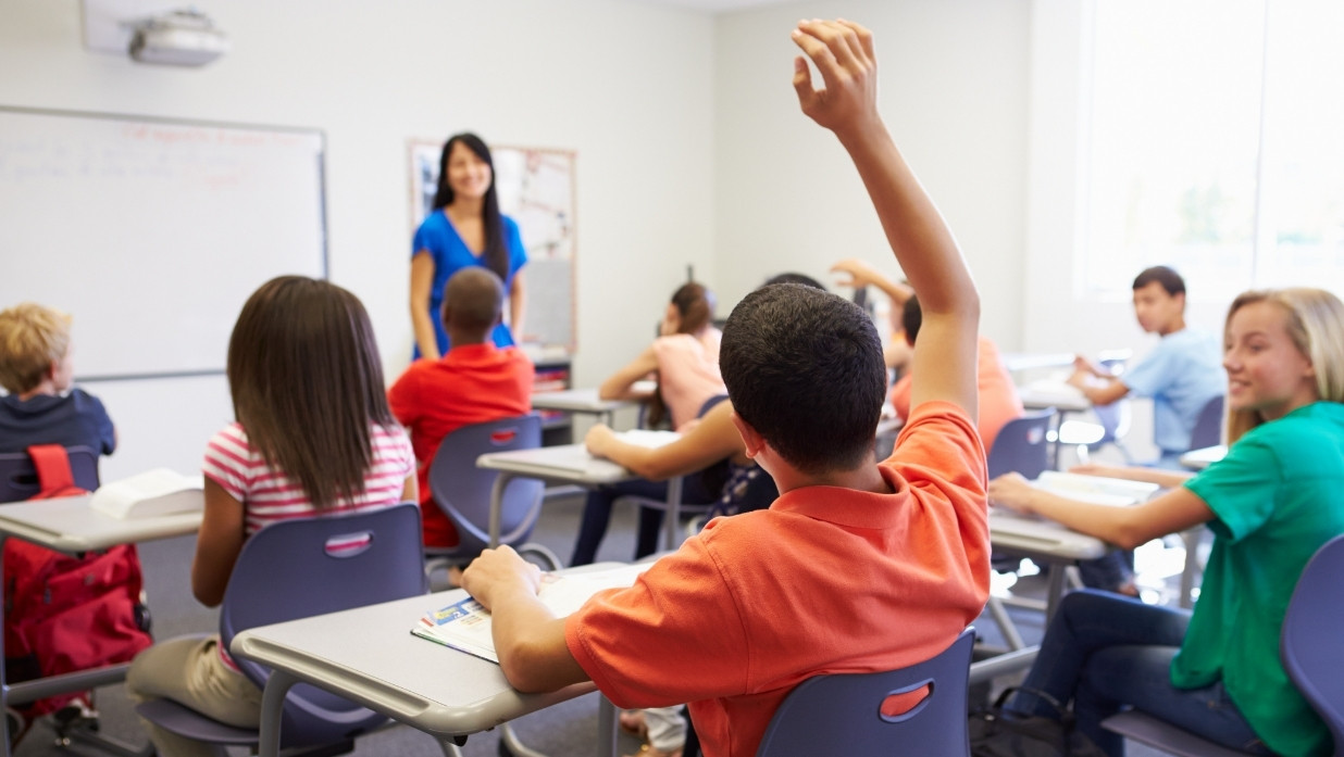 Kids in a class with their teacher and asking questions.
