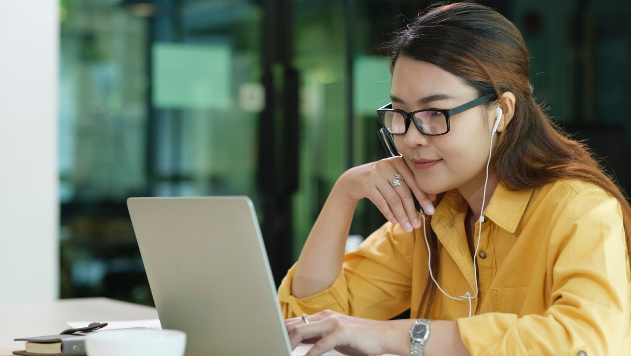 Person watching and listening to her computer screen. Has on glasses to see.