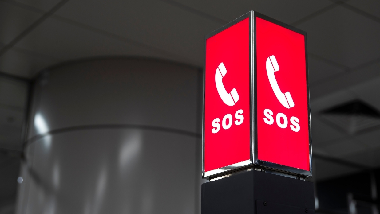 Bright red SOS emergency phone sign in a public building in Japan, indicating available help in urgent situations.