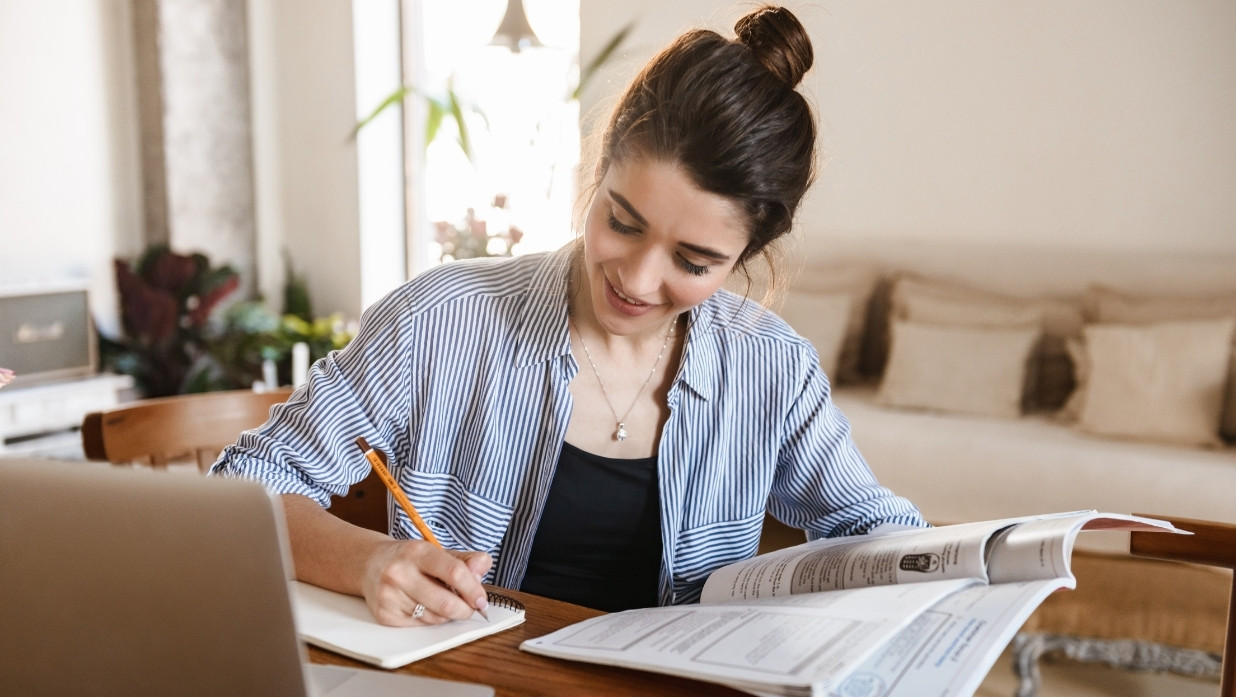Woman studying at her home. Writing down notes.