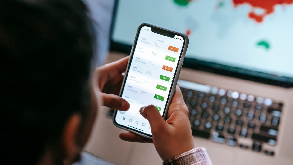 Photo of a man looking at conversion rates on his phone, an app.