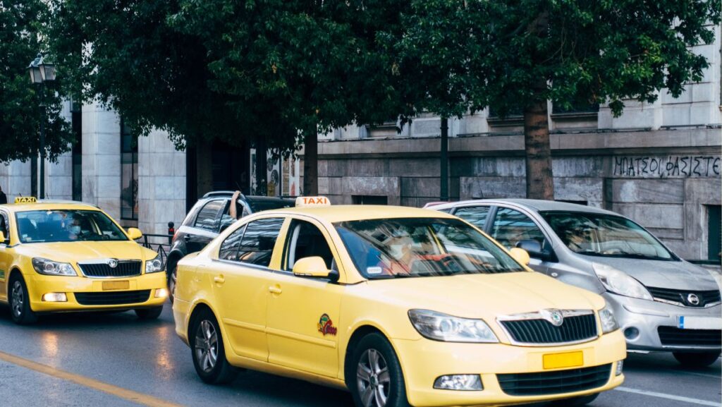 Image of a taxi cab driving on a road with others.